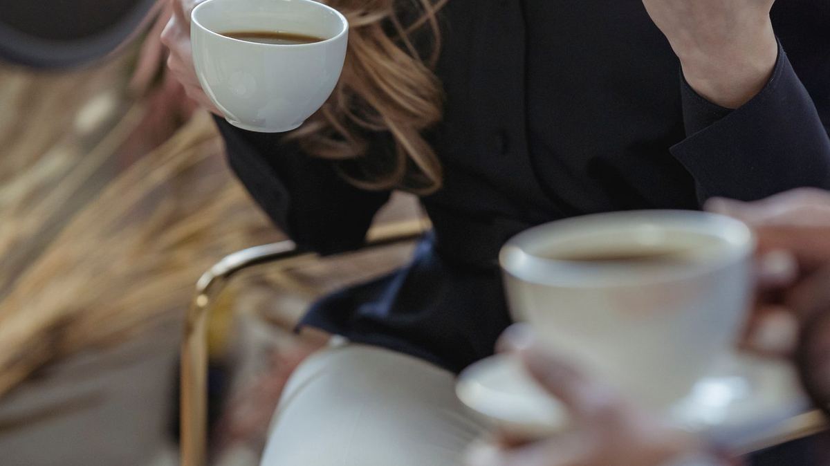 Twee mensen in gesprek met koffiekopjes in de hand